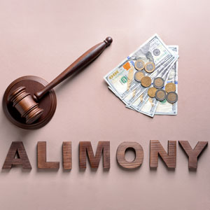 The word ALIMONY spelled in wooden letters with a gavel and money.